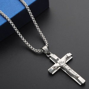 Macro detail of silver stainless steel cross pendant with 3D Jesus relief on box chain