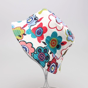 Detail showing a colorful floral print bucket hat on a white metal display stand