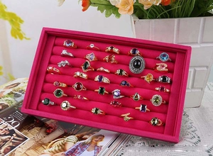 Macro view of rose red velvet jewelry tray displaying multiple gemstone rings