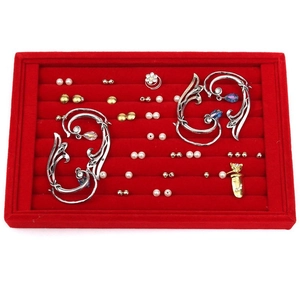 Close-up of pearl and gold earrings displayed on a premium red velvet jewelry tray