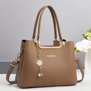 Detail der braunen Handtasche aus Kieselleder mit goldenen Elementen und Schriftzug
