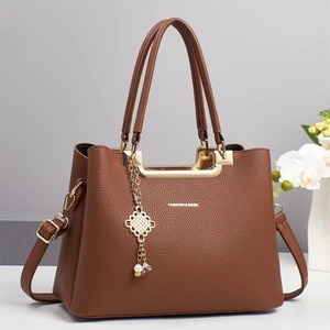 Detail der braunen Handtasche mit Litschi-Muster, Goldbeschlägen und Modeschrift