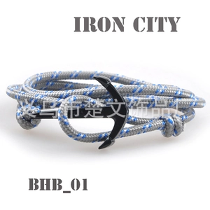 Detail view of woven nautical rope bracelet with a black metal anchor-shaped buckle clasp