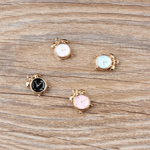 Flat lay of colorful enamel alarm clock charms for DIY jewelry on a wooden background