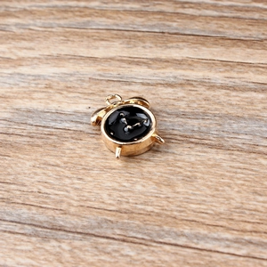 Detailed close-up of a gold alloy alarm clock charm accessory on a wooden background