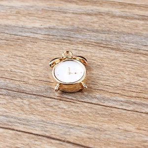 Close-up of golden clock charm pendant with white dial on a wooden background