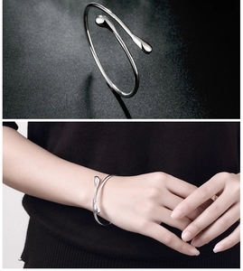 Detail eines silbernen Tropfen-Armreifs mit poliertem Finish und Tragebeispiel am Handgelenk