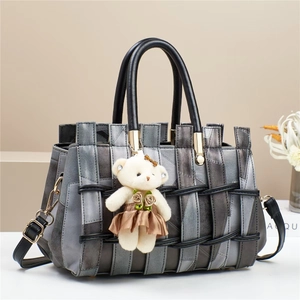 Gray patchwork crossbody bag with leather handles and white teddy bear charm