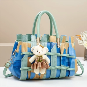Detailed weave of the blue and green leather handbag featuring a white teddy bear charm