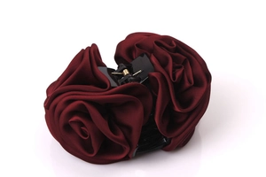 Vista de cerca de la pinza para el pelo con rosas de satén granate y textura floral