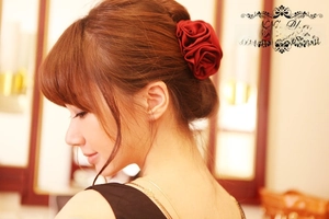 Detail of red satin double rose hair clip showing fabric texture on dark brown hair