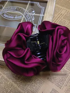 Detailed view of dark burgundy fabric rose hair clip with a sturdy black shark claw grip