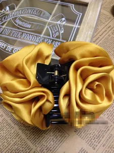 Detail of elegant golden satin fabric rose flower hair claw clip with vintage background