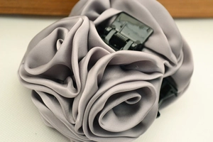 Primer plano detallado de pinza para el pelo de rosa satinada gris con pliegues