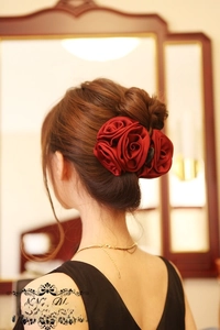 Elegant burgundy satin rose hair clip styled on a woman's bun for a vintage evening look