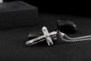 Macro detail of silver double-layer cross pendant necklace with Jesus on black stones