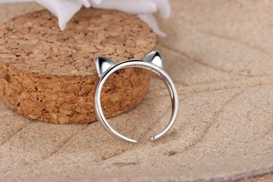 Close-up of a silver cat ear open ring on a cork stand with minimalist warm background
