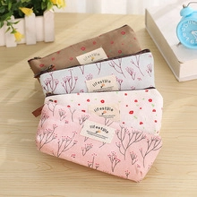 Set of four floral canvas pencil pouches in brown, blue, white, and pink on a wooden table