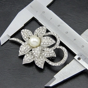 Macro shot of a 5cm silver flower brooch with crystal petals and a large center pearl