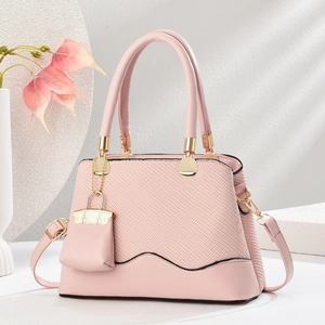 Pink textured fabric and smooth leather handbag with gold metal handles and flower accents