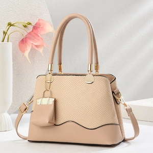 Elegant apricot woven leather handbag with circular handles and decorative mini bag charm