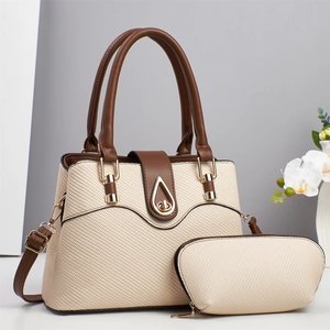 Detail of beige woven tote bag set with brown leather trim and golden teardrop twist lock