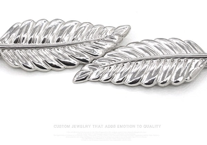 Close-up of silver elastic chain belt featuring polished metal leaf buckle detail