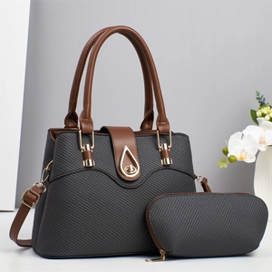 Detail of woven texture handbag with brown leather handles and golden metal clasp