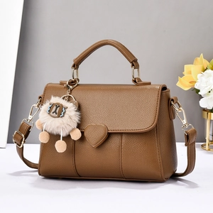 Détail d'un sac en cuir marron avec motif cœur et breloque en peluche lion mignon