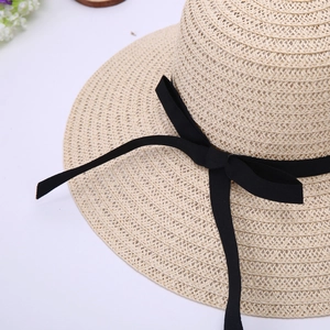 Close-up of woven straw texture and elegant black ribbon bow on summer sun hat