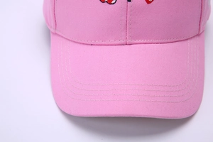 Close-up of pink cotton baseball cap with neat stitching details and red embroidery