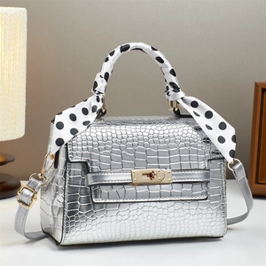 Detail of silver crocodile pattern bag with polka dot scarf and golden metal lock