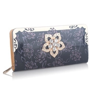 Detail of navy long wallet featuring floral print and metal flower charm with rhinestones
