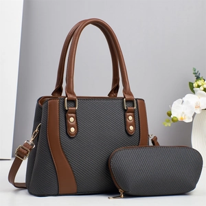 Detail view of the dark grey woven texture fabric and brown faux leather handbag set
