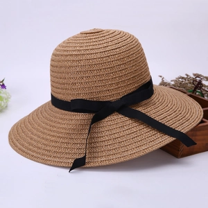 Detail of a foldable straw beach hat with elegant black ribbon and wavy brim for women