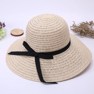 Detail of a beige straw hat with a wide brim and an elegant black silk ribbon bow