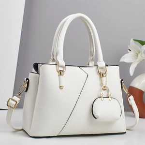 Elegant ivory faux leather handbag with gold accents and a matching charm pendant