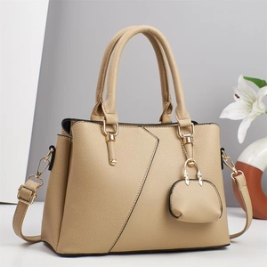 Elegant beige pebbled leather handbag with diagonal stitching and mini charm pendant