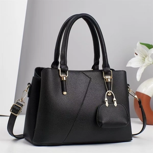 Detail of black litchi grain leather handbag featuring V-shape stitching and gold hardware