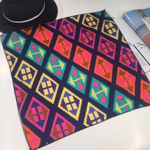 Detail of square silk scarf featuring a colorful geometric diamond pattern and black edges