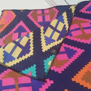 Detailed close-up of geometric pattern silk scarf with Made in Korea label and stitching