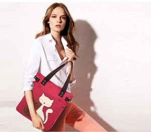 Red canvas tote bag with cat pattern detail carried by a model in casual white shirt