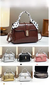 Detail of crocodile pattern leather handbag with polka dot scarf handle and metal clasp