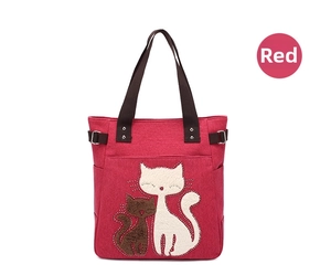 Detail of red canvas tote bag with cat embroidery and durable brown strap