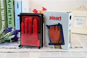 Macro detail of red pinart 3D clone toy showing plastic needles and box packaging