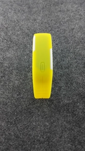 Détail du bracelet LED jaune en silicone avec bouton tactile sur fond en tissu gris