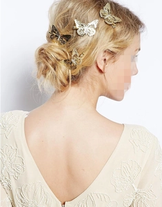 Detailed view of three gold butterfly hair clips worn on elegant bridal hairstyle
