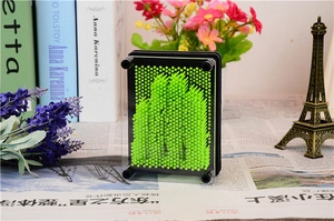 Detail of 3D pin art toy in bright green with hand impression on a decorative setup
