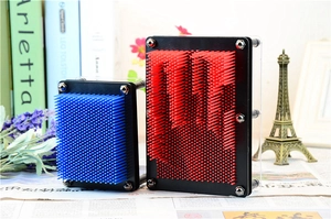 Creative 3D pin art toy with red M shape and blue model on a decorative desk