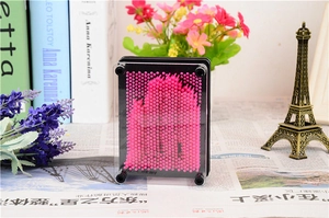 Detail of 3D pin art toy with pink plastic pins and black frame on a creative desk